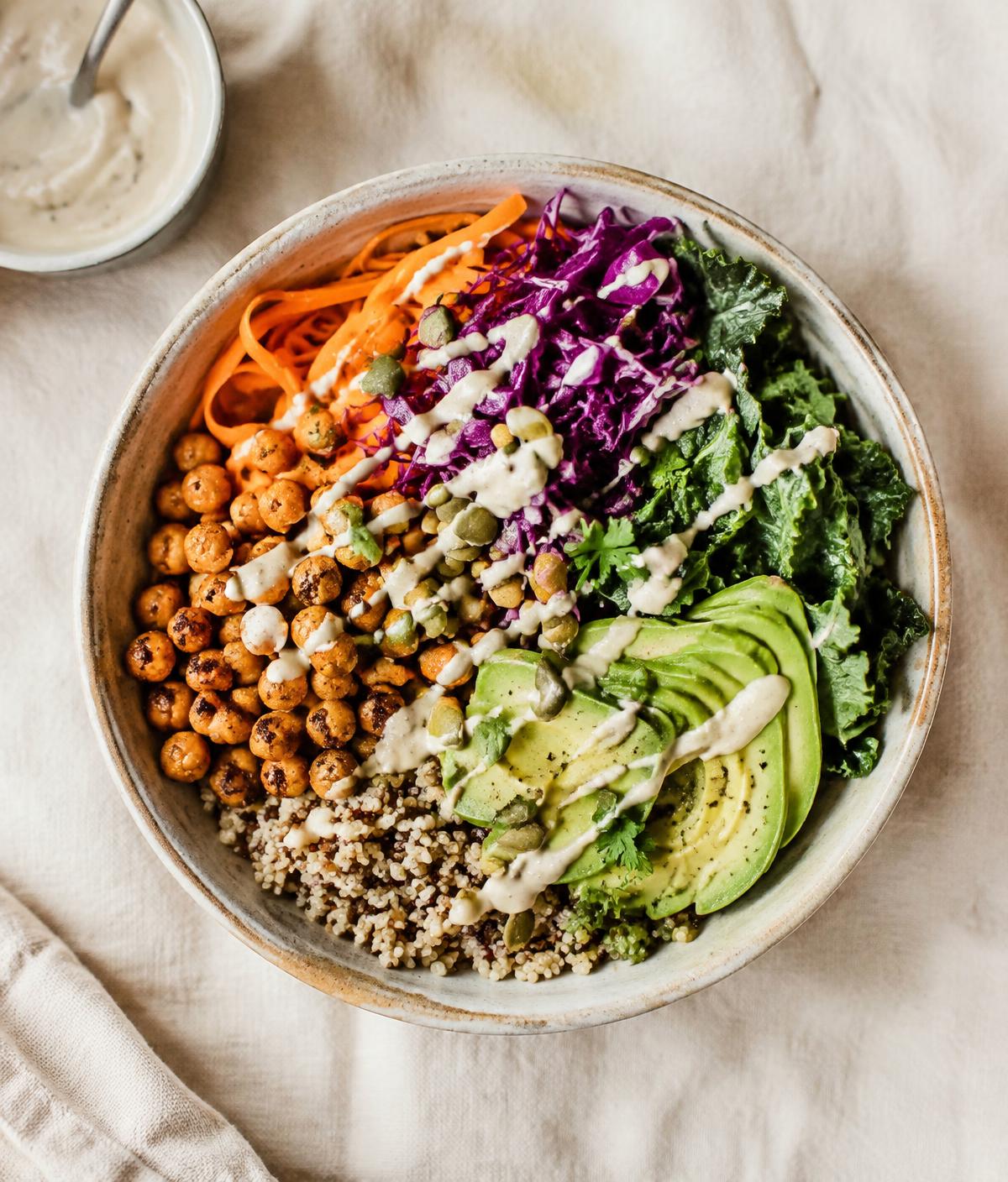 Overhead view of a colorful vegan bowl with quinoa, roasted chickpeas, avocado and greens